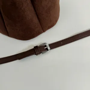 Braune Wildleder Beuteltasche Detail mit schmalem Schulterriemen und silberner Metallschnalle.