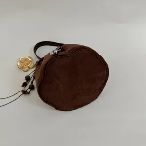 Braune Veloursleder Beutel-Tasche Detail mit Blütenboden, Metallverschluss und Perlenanhänger.