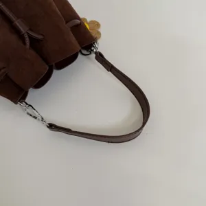 Braune Wildleder Beuteltasche Detailansicht, zeigt feine Metallbeschläge und Verarbeitung.