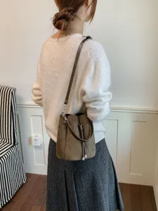 Detailansicht der braunen Wildleder Beuteltasche mit verstellbarem Schultergurt Design.