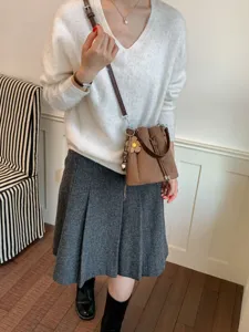 Detailaufnahme des braunen Wildleder-Beutelstoffs mit schönem Blumenanhänger am Model.
