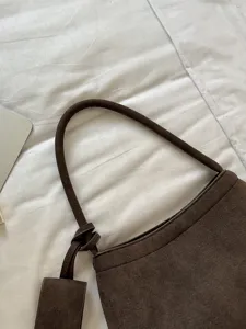 Close-up detail of vintage brown suede shoulder bag, soft texture handle and knot decoration.
