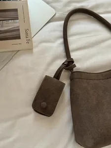 Detail view of a retro brown suede shoulder bag with small pouch, stylish casual commuter bag.