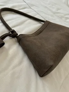 Detail view of retro brown suede shoulder bag with long strap, minimalist design for commute.