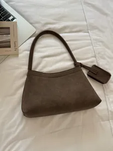 Retro brown suede shoulder bag for women, chic commuting hobo bag with small charm accessory.