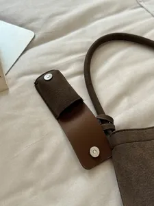 Brown suede shoulder bag detail, vintage chic style accessory, metal magnetic closure.