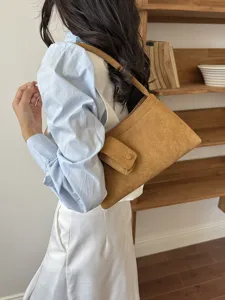 Detail view of a vintage style brown suede shoulder bag with chic flap pocket design.