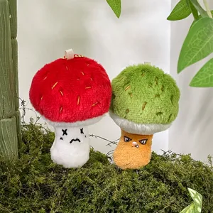 Primo piano di ciondoli in peluche a forma di fungo carino su sfondo di muschio verde.