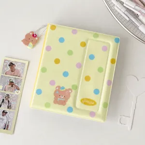 Yellow polka dot photocard binder detail, cute bear pendant, aesthetic Kpop album storage.