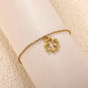 Primer plano detallado de una pulsera de cadena dorada con un colgante de trébol hueco.