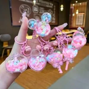 Close-up detail of cute pink liquid quicksand cartoon keychains and bag pendants.