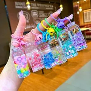 Close-up detail of colorful liquid glitter keychain bottles with cute bells, creative hanging accessory.