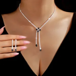 Close-up detail of rhinestone flower pendant necklace and tassel earrings set, sparkling crystal details.