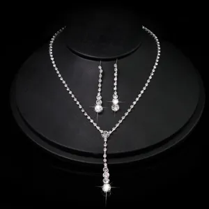 Close-up detail of silver rhinestone Y-necklace and matching dangle earrings set on black display.