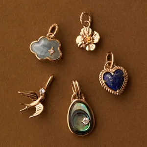 Vue détaillée de divers pendentifs dorés assortis incluant nuage, fleur et cœur pour bijoux.