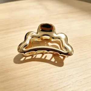 Gold metal hair claw clip with wave design, elegant shark clip for thick hair styling detail.