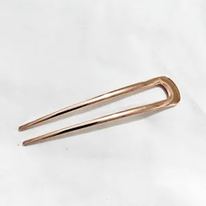Détail d'épingle à cheveux en métal rose gold minimaliste, accessoire de coiffure.