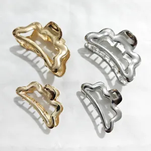 Detailed close-up of metallic hair claws featuring unique irregular wave designs in gold and silver.