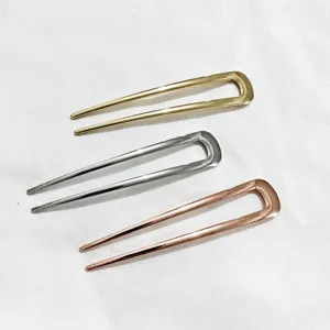 Gros plan d'épingles à cheveux en métal en forme de U en or, argent et or rose vif.