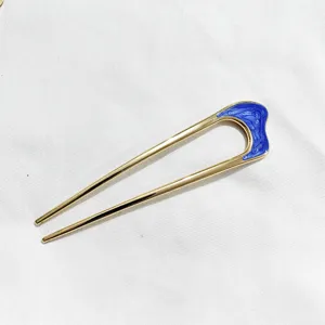 Vue détaillée de l'épingle à cheveux en U dorée avec accent bleu brillant pour coiffures élégantes.