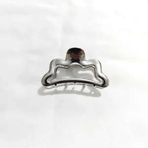 Silver metal hair claw clip detail shot, elegant wave design for daily styling and secure hold.