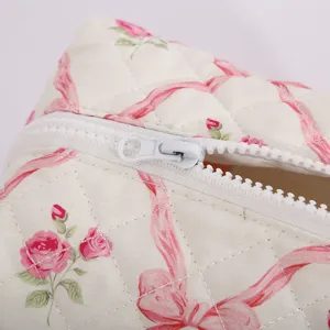 Trousse de maquillage matelassée avec motif floral et ruban romantique en gros plan.
