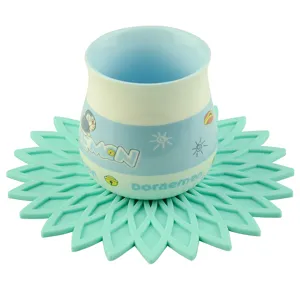 Bonita taza de cerámica Doraemon con posavasos de silicona con flor verde para uso doméstico diario.