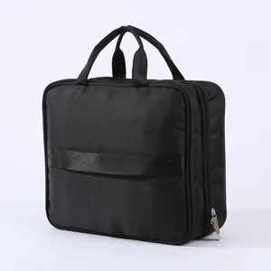 Portable travel toiletry bag with large capacity, dual handles and strap. Black cosmetic organizer.