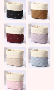 Quilted cosmetic storage bag detail showing multiple color variants and bow embroidery.