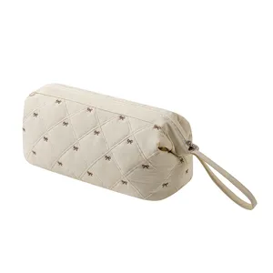 Beige quilted bow storage bag, portable travel pouch for hair dryer and accessories.