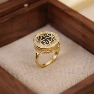 Vista detallada de un anillo dorado vintage con circonitas y diseño de trébol negro.