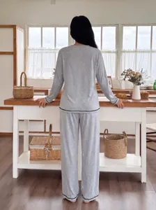 Detail shot showing back view of soft grey loungewear set with dark piping in bright room.