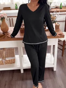 Detail shot of black long sleeve pajamas set with v-neck and white stitching trim.