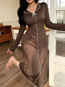 Detalle de camisón marrón de manga larga, ropa de dormir cómoda con lazo y borde blanco.