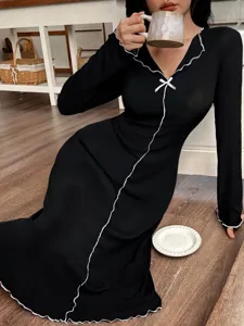 Vista detallada del camisón negro de manga larga con ribete de lechuga y lazo.