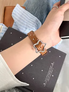 Gros plan detaille du bracelet de montre en cuir marron avec boucle d'etoile unique.