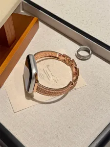 Détail de bracelet de montre en métal scintillant de strass, accessoire or rose sur plateau.