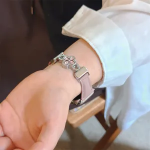 Gros plan détaillé sur le bracelet de montre en cuir rose pour Apple Watch avec un pendentif trèfle.