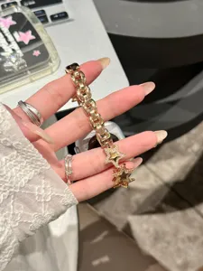 Gros plan détail du bracelet de montre en métal or rose luxueux avec des breloques étoiles.