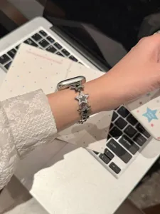 Gros plan détaillé d'un bracelet de montre scintillant en métal étoilé et strass au poignet.