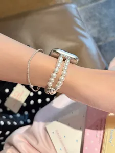 Nahaufnahme eines Perlen-Uhrenarmbands mit doppelten Strängen und einem Herz-Verbinder.