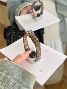 Vista dettagliata del cinturino in pelle marrone con eleganti borchie sferiche metalliche.