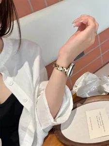 Détail du bracelet de montre en métal doré avec des étoiles creuses pour un style élégant.