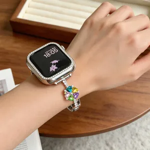 Gros plan détaillé du boîtier de montre en strass et du bracelet en métal trèfle en cristal coloré.