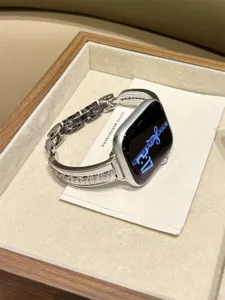 Primo piano del cinturino per orologio in metallo e zirconi scintillanti in un vassoio di legno.