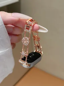 Nahaufnahme eines funkelnden, sternverzierten Metall-Charm-Uhrenarmbands in elegantem Roségold.
