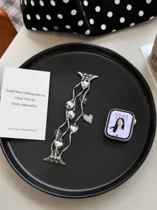 Detailopname van het kralen hart hanger horlogebandje gepresenteerd op een zwarte tray.