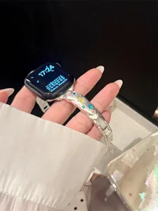 Nahaufnahme des metallischen, geknitterten Uhrenarmbands mit bunten Kristallsternen.
