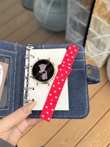 Detail view of a stylish smartwatch with red heart silicone strap inside a denim case.