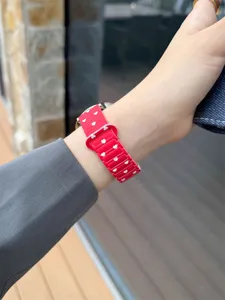 Detailed view of the red silicone watch strap with white heart pattern, soft and comfortable.